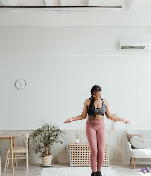 Woman in activewear performing a light, controlled cardio movement in a bright, minimalist room.